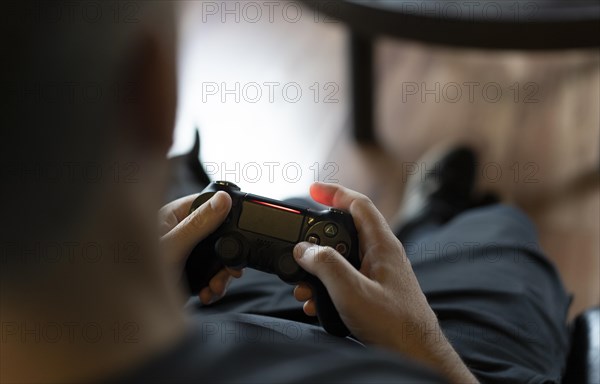 Close-up of an adult man's hands holding a joystick while playing a video game on a console. Copy space
