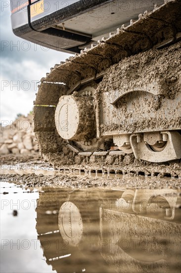 Tracked excavator in dirt with puddle