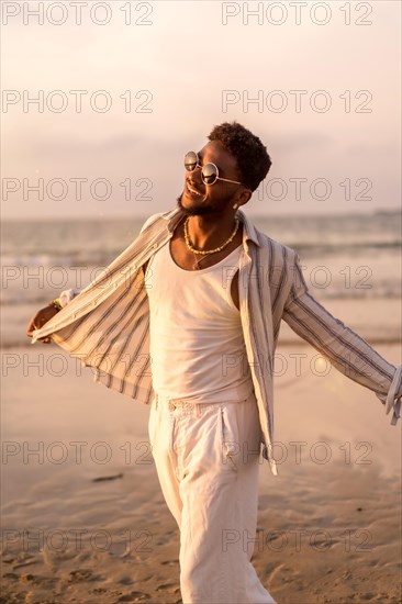 Portrait of attractive black ethnic man enjoying summer vacation by the sea feeling free