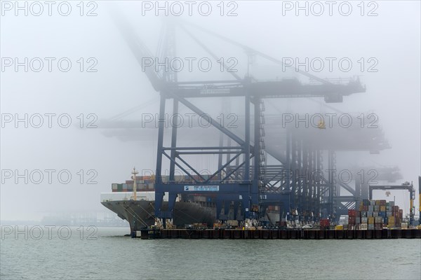 Foggy weather low visibility container ship cranes at quayside