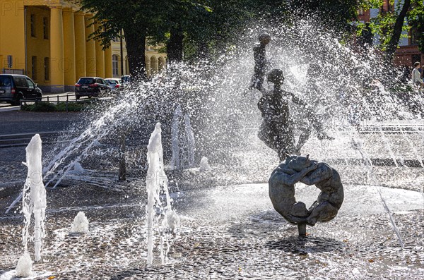 Urban scene at the fountain of joie de vivre on the Universitaetsplatz in the backlight