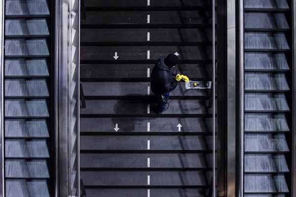 A cleaner wipes a staircase marked with arrows for the respective walking directions