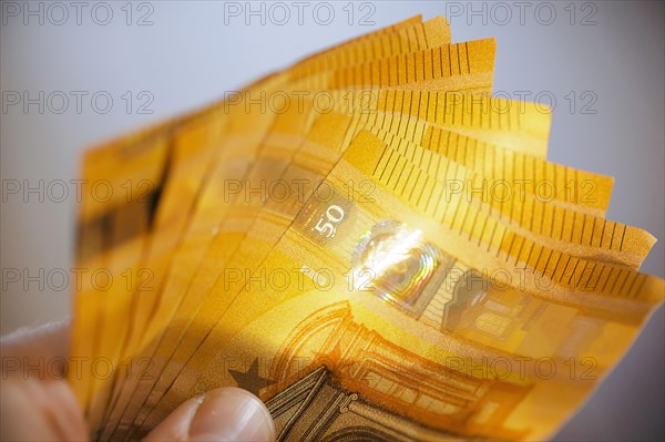 Symbolic photo on the subject of cash. 50 euro banknotes are held in one hand. Berlin