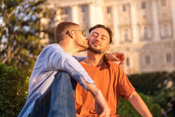 Portrait of gay newlyweds sitting in the park at sunset in a park in the city
