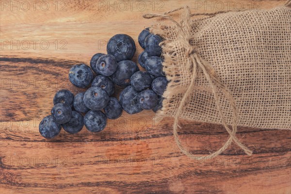 Fresh blueberries in a raffia bag on a wooden table