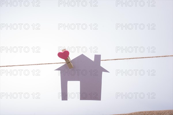 Little paper house attached to a string with a heart clip