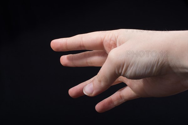 Five fingers of a child hand partly seen in black background