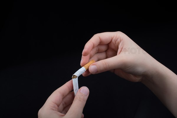 Hand is breaking a cigarette on a black background