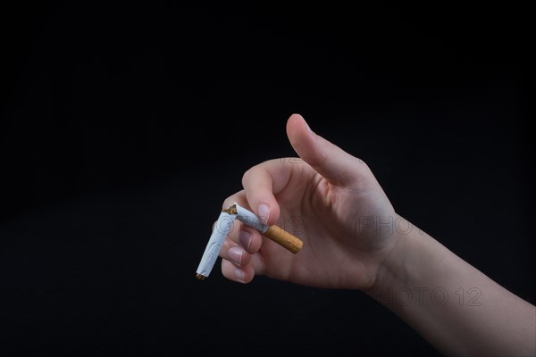 Hand is breaking a cigarette on a black background
