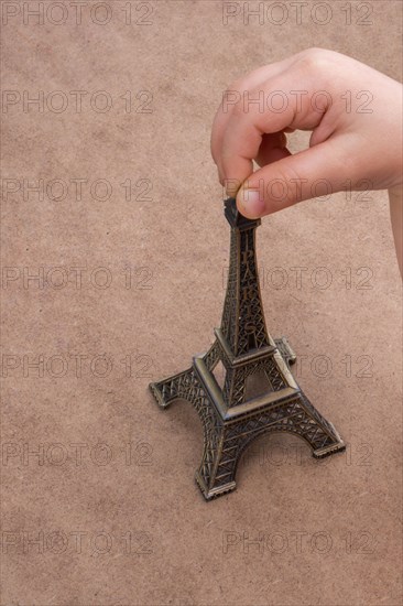 Child holding the little model of Eiffel Tower in hand