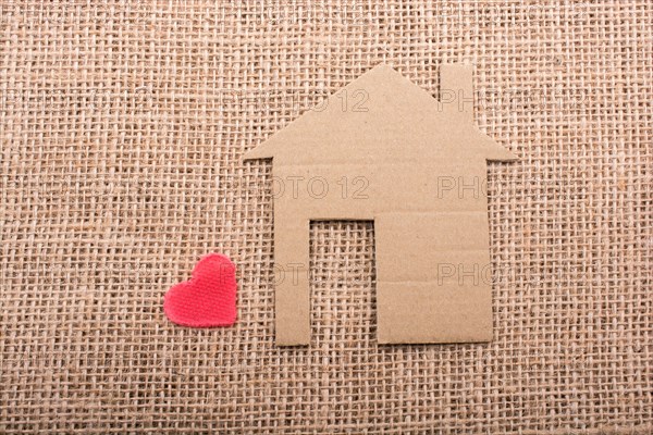 Heart shape beside paper house with a canvas background