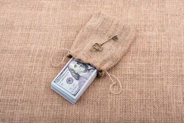 Retro key and bundle of US dollar in a sack on a canvas