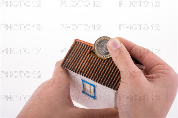 Hand dropping coin into the moneybox in the shape of a model house