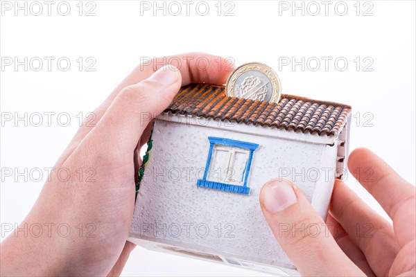 Hand dropping coin into the moneybox in the shape of a model house