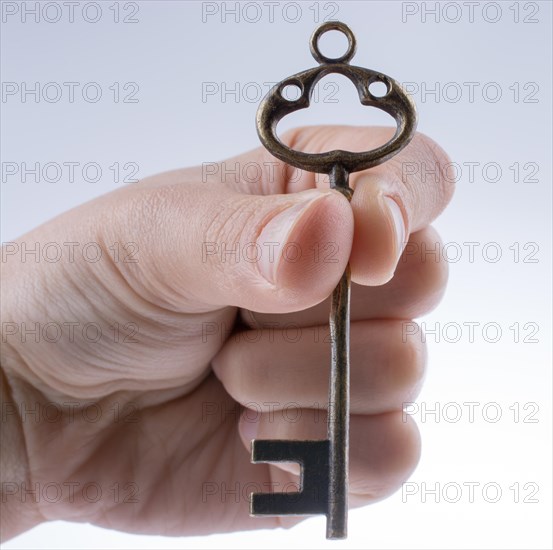 Hand holding a retro styled metal key on a white background