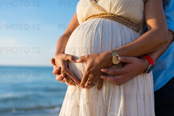 Pregnant maternity latin woman on the beach at sunset