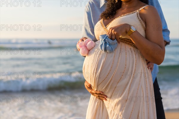 Pregnant maternity latin woman on the beach at sunset