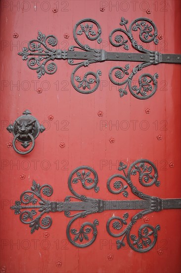 Red church door with fittings and decorations of the Romanesque St Ägidius Abbey Church