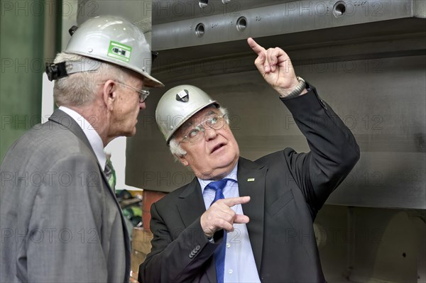 Minister President Winfried Kretschmann with Martin Herrenknecht - both wearing safety helmets - during a visit to Herrenknecht AG