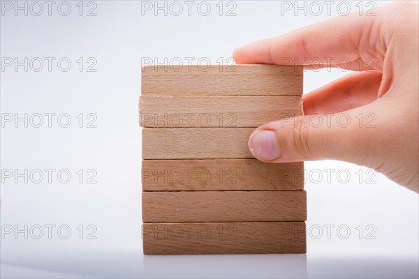 Hand holding wooden domino on a white background