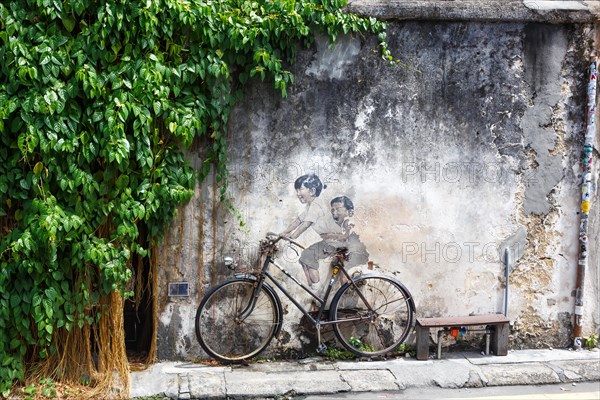 Street art boy and girl on bicycle on a wall in George Town on Penang Island