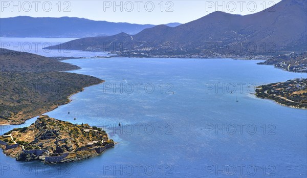 Aerial view of clear sea waters of harbor between Spinalonga island and peninsula