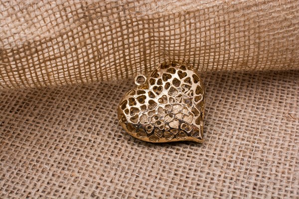 Heart shaped gold color metal object on canvas