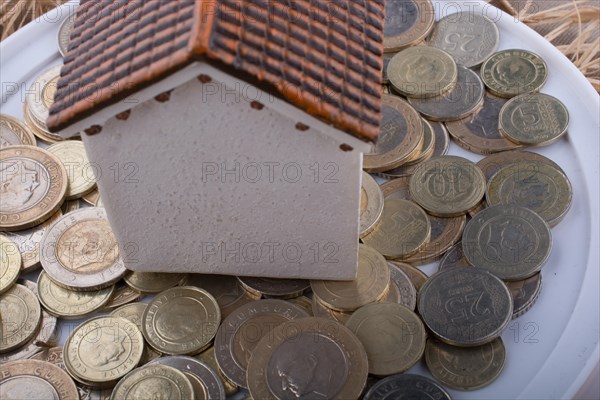 Turkish Lira coins by the side of a model house on white background