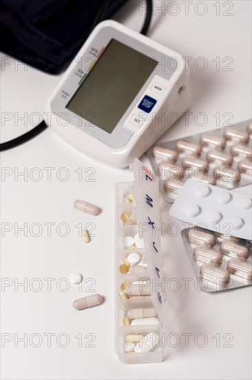 Daily pill box with blood pressure monitor in the background isolated on a white background