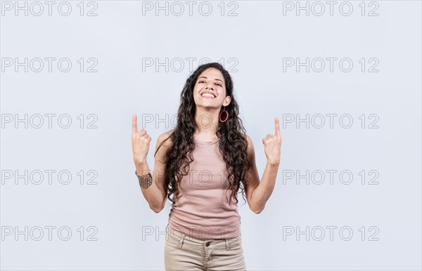Young girl pointing an advertisement with fingers up. Smiling woman pointing with both fingers up isolated. People recommending with fingers up