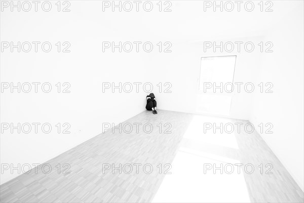 Depressed Woman Sitting on the Floor in a Corner in a Empty Room at Home in Switzerland