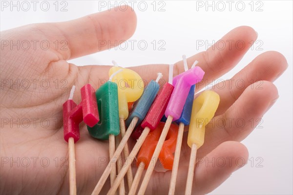 Hand holding letters made of candles on sticks