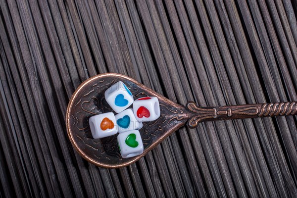 Colorful love cubes in a spoon on a straw mat