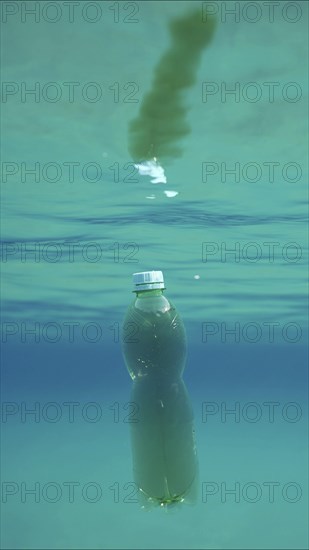 Green plastic bottle drifting under surface of blue water. Plastic pollution of Ocean