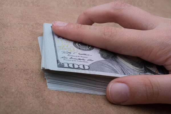 Hand holding banknote bundle of US dollar on a linen canvas background