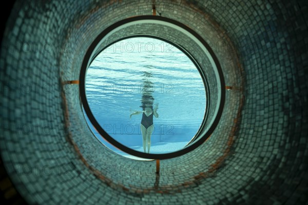 Woman Standing in the Ship Porthole in Underwater in Swimming Pool in a Sunny Day in Switzerland