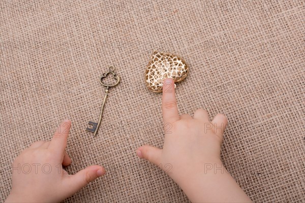 Heart shaped gold color metal object in hand