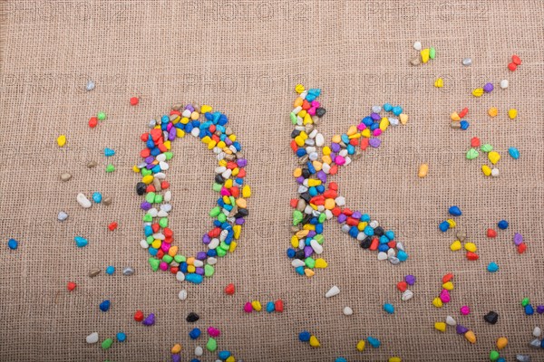 Colorful pebbles form the word OK on canvas ground