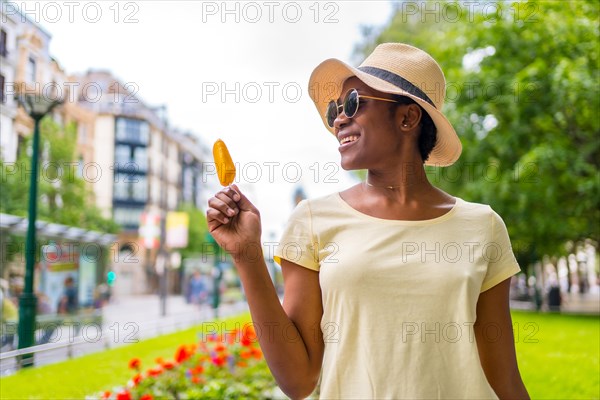 African black ethnicity woman eating a mango ice cream in the city