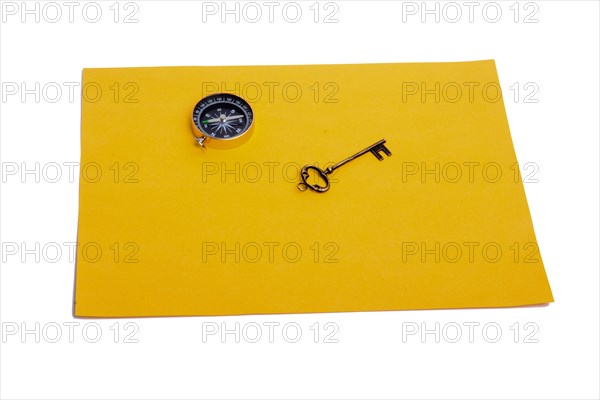 Key and compass on a sheet of colored plain paper with a white background