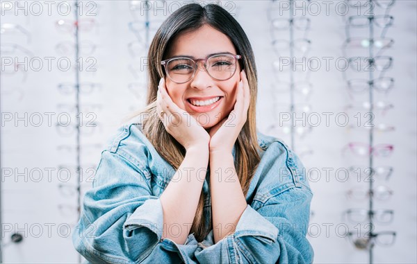 Happy girl modeling glasses in an optical lens store. Portrait of beautiful girl modeling glasses in an optical store