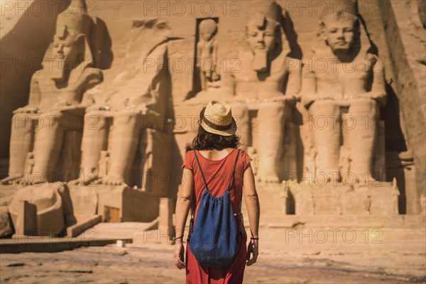 A young tourist in a red dress entering the Abu Simbel Temple in southern Egypt in Nubia next to Lake Nasser. Temple of Pharaoh Ramses II
