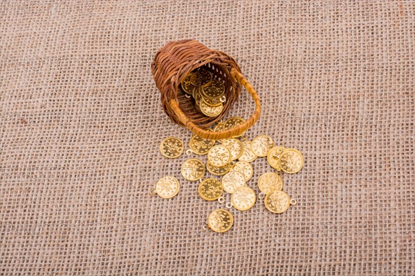 Fake gold coins out of a little basket on canvas