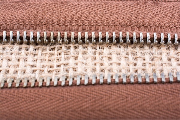 Parts of the brown color zipper on linen canvas background