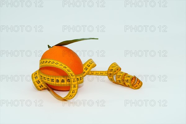 Fresh orange with leaves surrounded by a tape measure isolated on white background and copy space