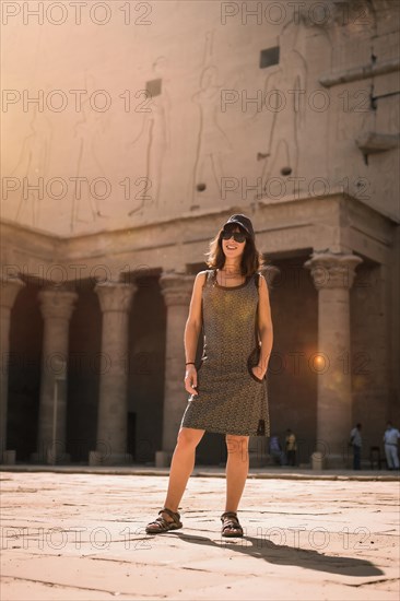 A young tourist wearing a cap visiting the Edfu Temple at sunrise in Aswan. Egypt