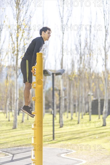 Young man doing climbing vertical exercise in the park