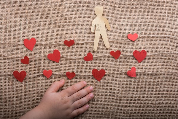 Paper man and heart icons on linen threads on canvas