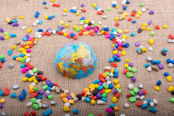 Globe in the heart form shaped by colorful pebbles