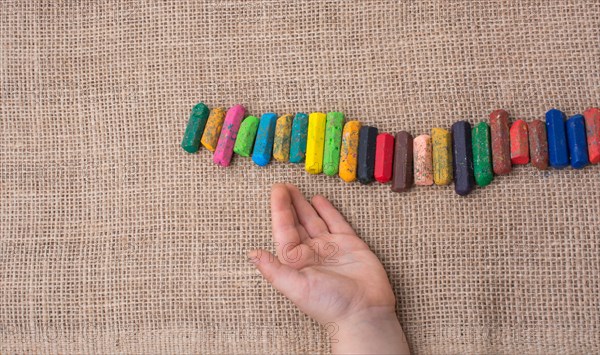 Toddlers hand putting crayons in line on canvas